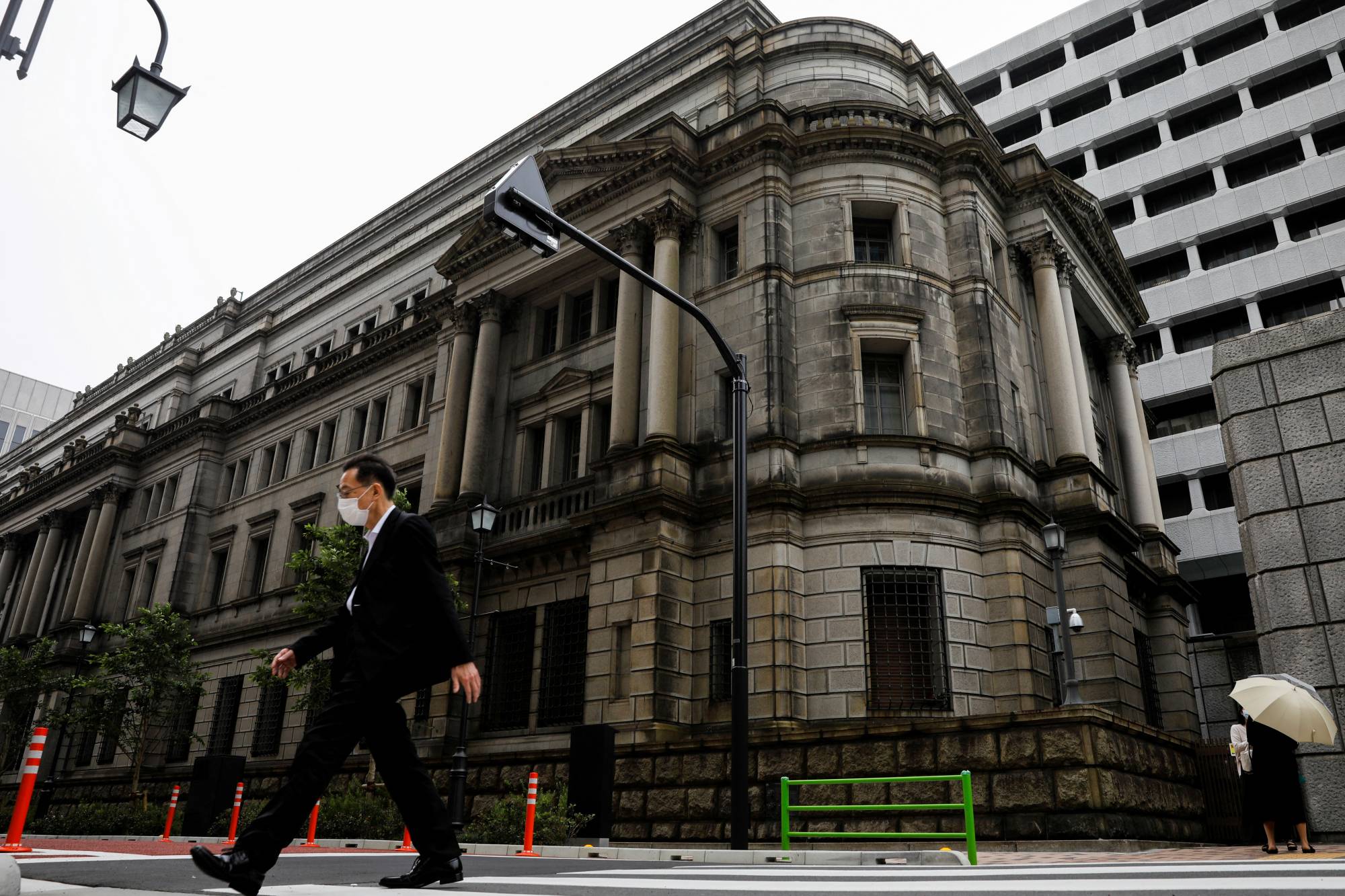 FILE PHOTO: A man wearing a protective mask walks past the headquarters of Bank of Japan amid the coronavirus disease (COVID-19) outbreak in Tokyo FILE PHOTO: A man wearing a protective mask walks past the headquarters of Bank of Japan amid the coronavirus disease (COVID-19) outbreak in Tokyo, Japan, May 22, 2020.REUTERS/Kim Kyung-Hoon/File Photo