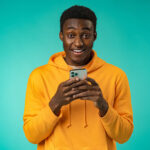 Afro american man using smartphone over isolated mint background