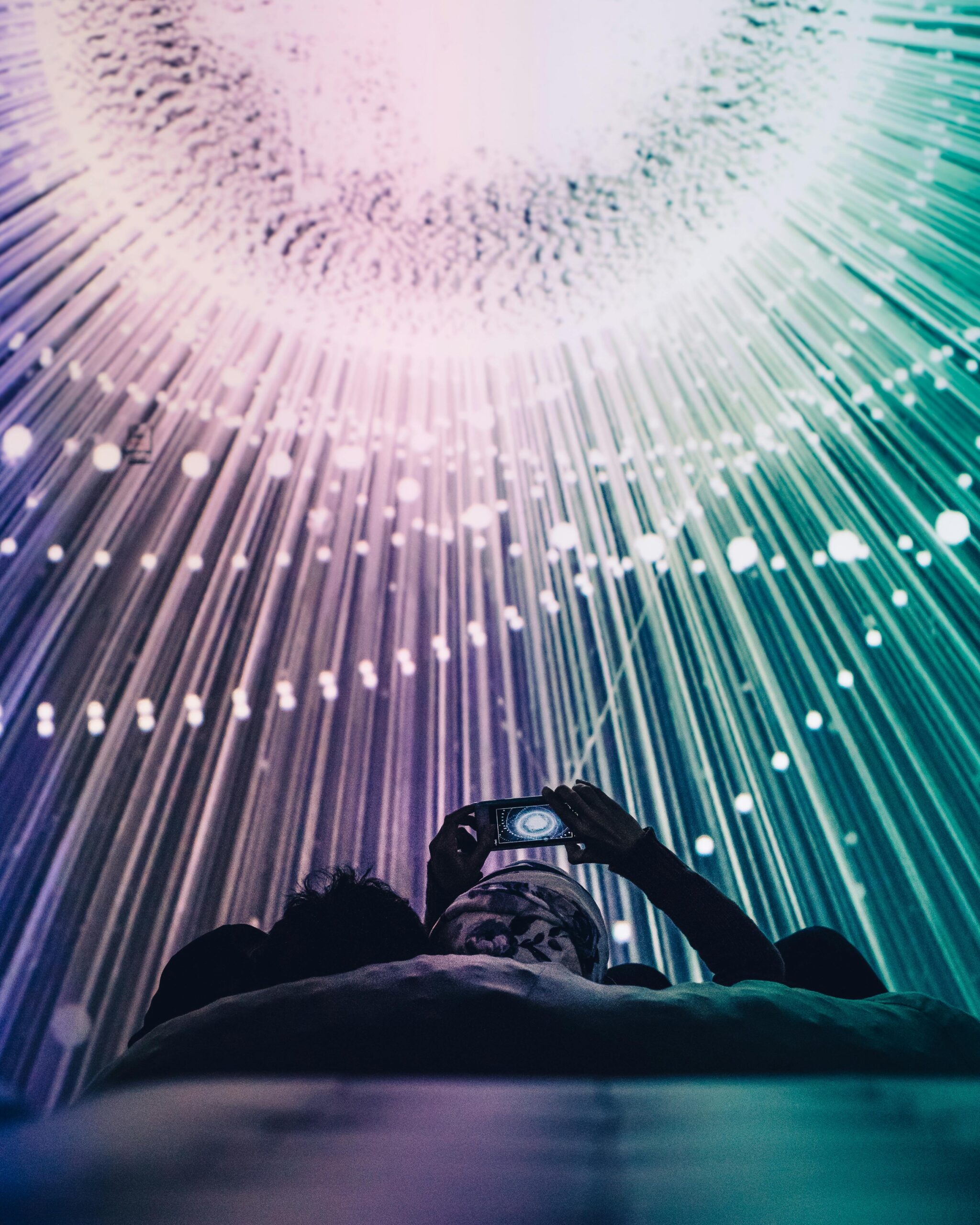 A person captures a captivating light display with a smartphone at a futuristic exhibit.